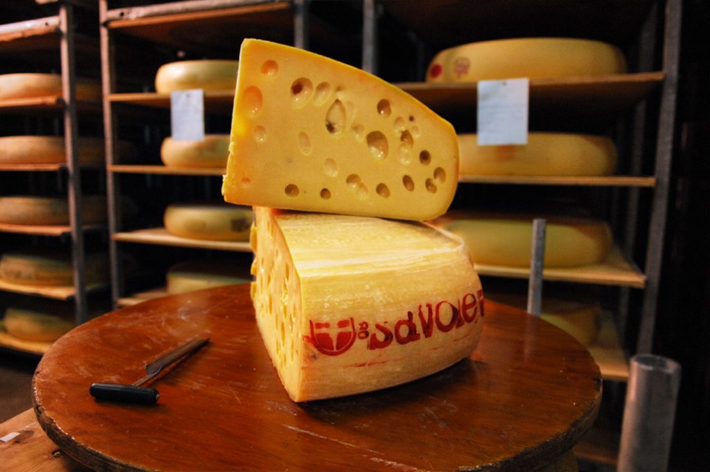 Two stacked wedges of Emmental de Savoie stacked on top of each other.  An invisible velociraptor sniffs suspiciously.